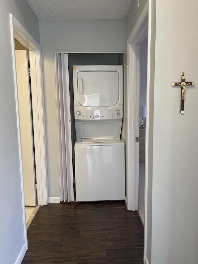 washroom with stacked washer and clothes dryer and a textured ceiling