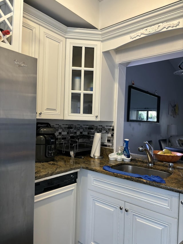 kitchen featuring sink, stainless steel refrigerator, white cabinetry, backsplash, and dark stone countertops