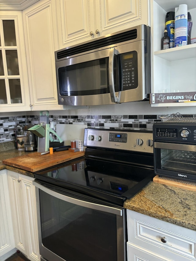 kitchen featuring dark stone countertops, white cabinetry, and appliances with stainless steel finishes