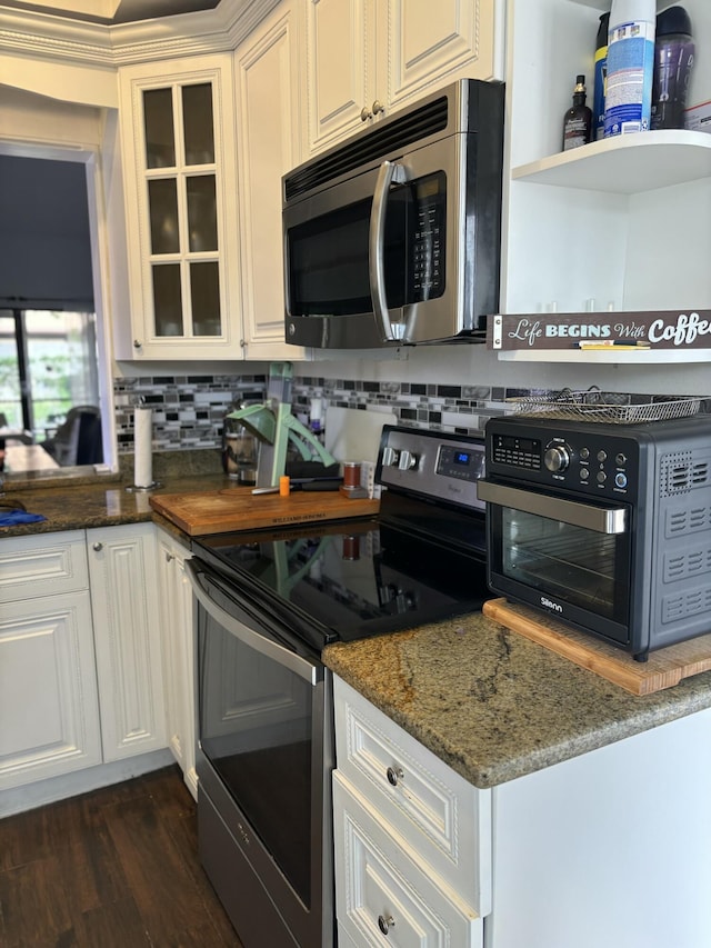 kitchen featuring white cabinetry, tasteful backsplash, dark stone counters, dark hardwood / wood-style floors, and stainless steel appliances