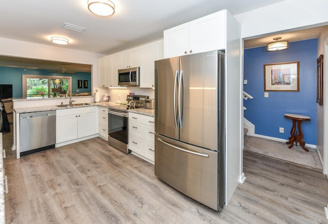 kitchen with sink, white cabinetry, appliances with stainless steel finishes, kitchen peninsula, and light stone countertops