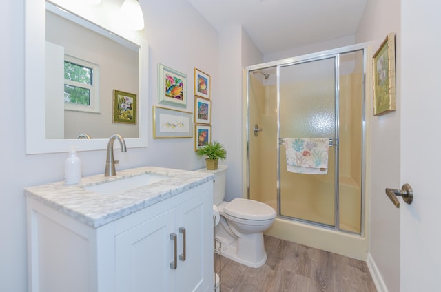 bathroom with wood-type flooring, toilet, vanity, and walk in shower