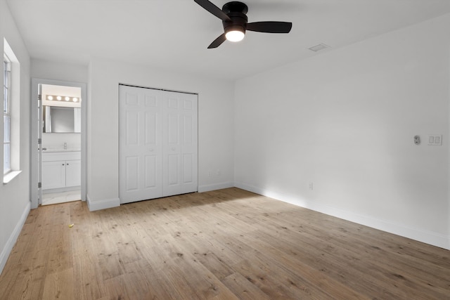 unfurnished bedroom featuring light hardwood / wood-style floors, connected bathroom, ceiling fan, and a closet