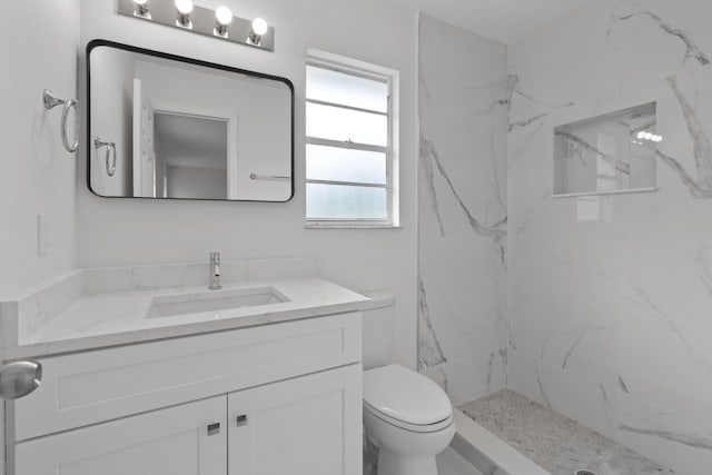 bathroom with vanity, a tile shower, and toilet