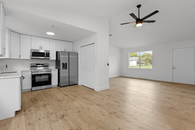 kitchen with sink, vaulted ceiling, light hardwood / wood-style flooring, stainless steel appliances, and white cabinets