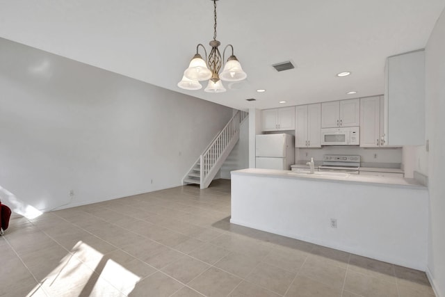 kitchen with white cabinets, hanging light fixtures, white appliances, kitchen peninsula, and an inviting chandelier