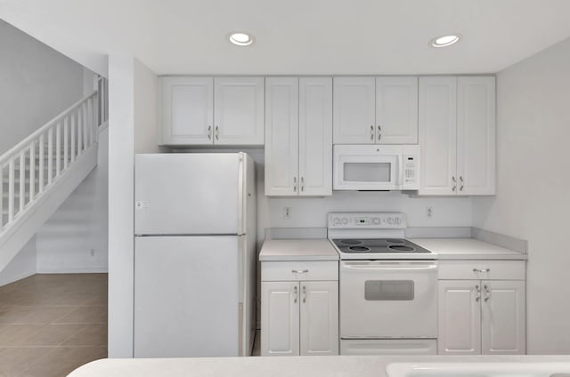 kitchen featuring white cabinetry, light tile patterned floors, and white appliances