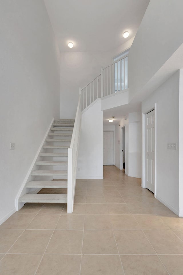 staircase featuring tile patterned flooring and a high ceiling