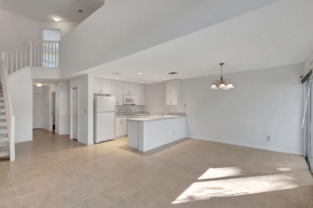 kitchen with white cabinetry, sink, white appliances, kitchen peninsula, and an inviting chandelier