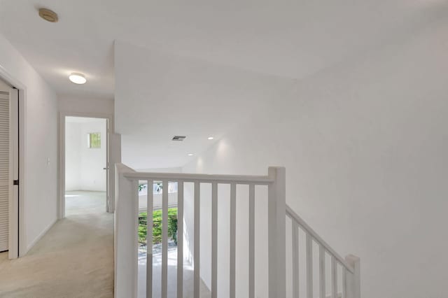 hallway with vaulted ceiling and light carpet