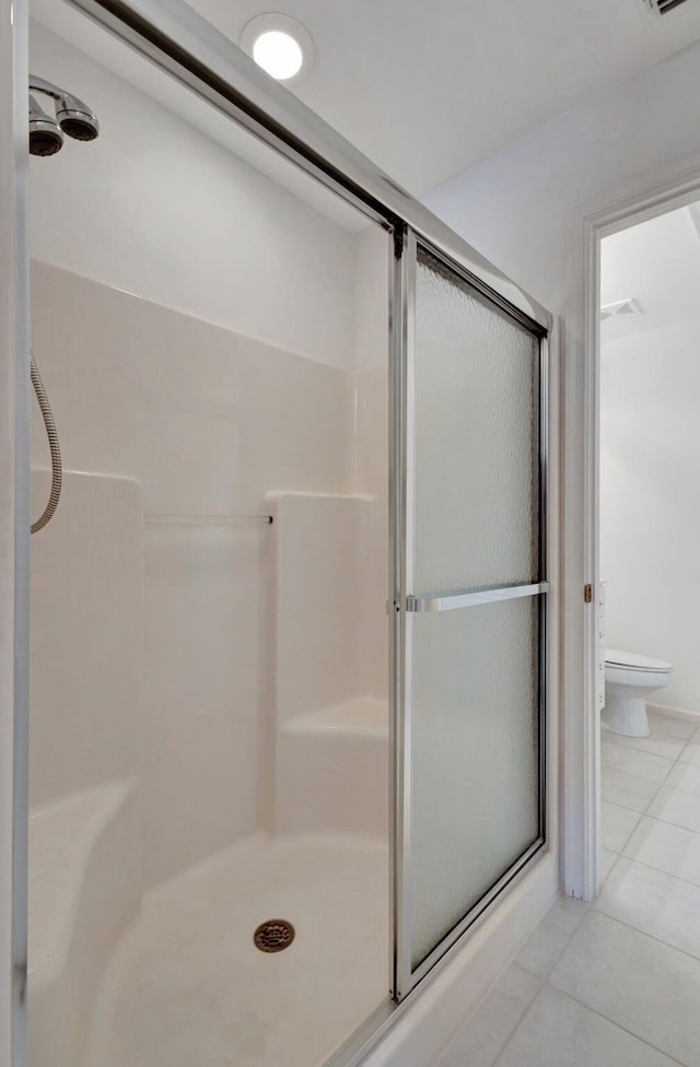 bathroom with toilet, tile patterned floors, and a shower with shower door