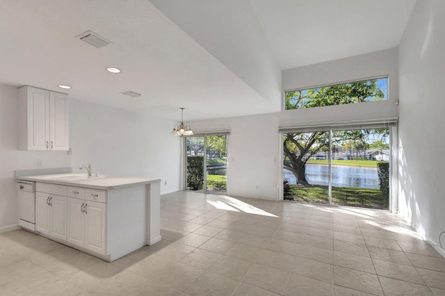 kitchen featuring sink, a water view, white dishwasher, pendant lighting, and white cabinets