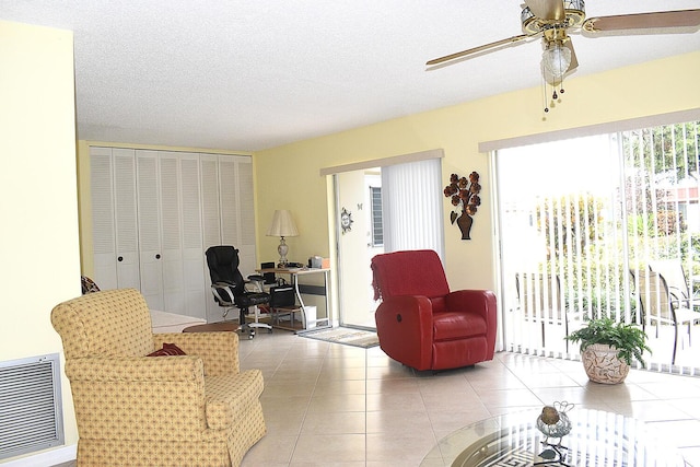 tiled living room featuring ceiling fan and a textured ceiling