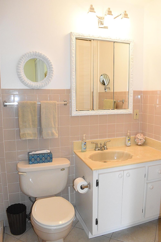 bathroom with vanity, toilet, tile patterned flooring, and tile walls