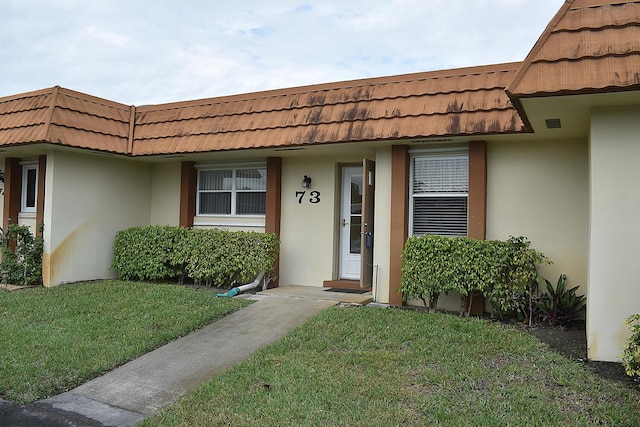 doorway to property featuring a lawn