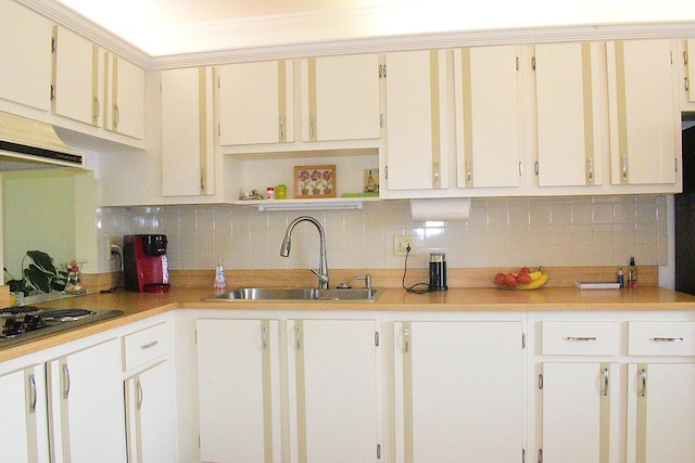 kitchen featuring stainless steel gas stovetop, sink, white cabinets, and decorative backsplash