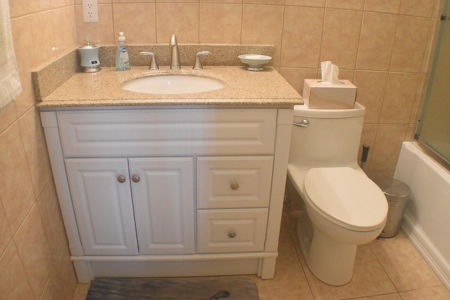 full bathroom featuring tile patterned floors, vanity, toilet, and tile walls