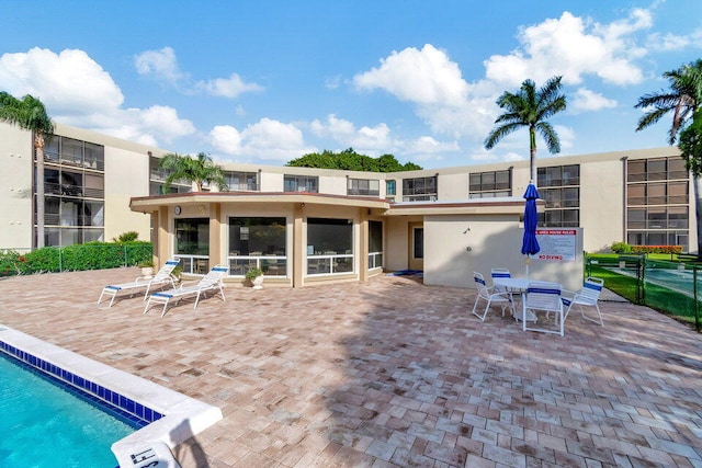 rear view of property with a patio, a community pool, and stucco siding