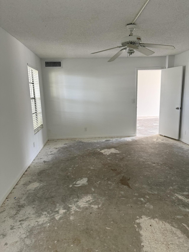 empty room featuring visible vents, ceiling fan, a textured ceiling, and unfinished concrete floors