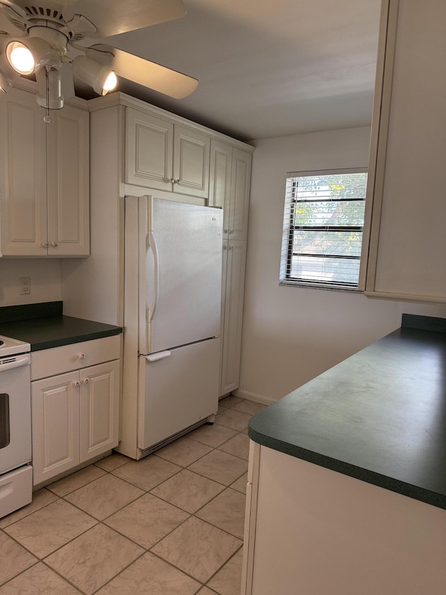 kitchen with white appliances, dark countertops, a ceiling fan, and white cabinets