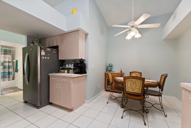 kitchen featuring stainless steel refrigerator with ice dispenser, light tile patterned floors, ceiling fan, and light brown cabinets