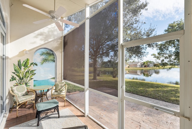 sunroom featuring a wealth of natural light, ceiling fan, and a water view