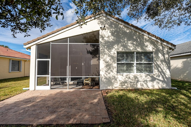 rear view of house with a yard, a patio area, and a sunroom