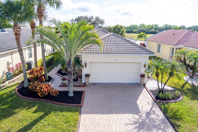 mediterranean / spanish-style home featuring a garage, central AC unit, and a front yard