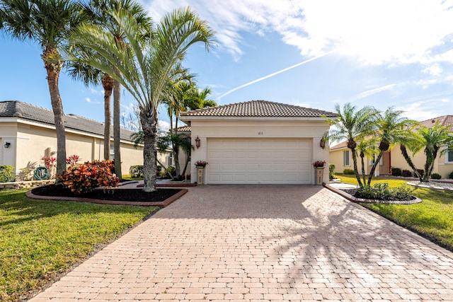 mediterranean / spanish house featuring a garage and a front lawn