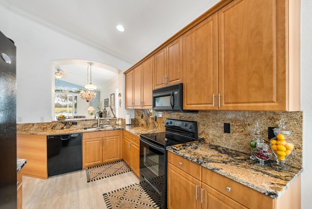 kitchen featuring stone countertops, backsplash, black appliances, crown molding, and light wood-type flooring