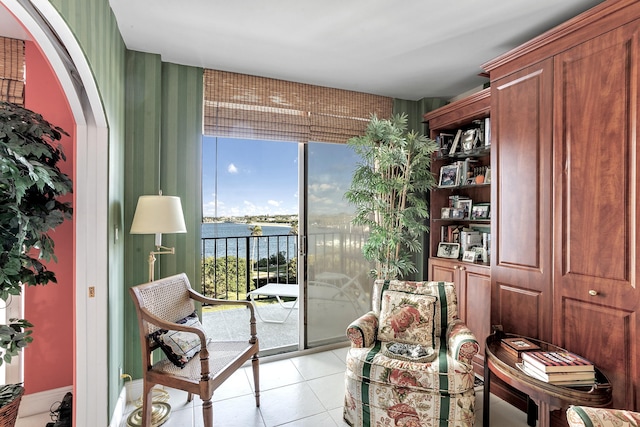 living area with light tile patterned flooring and a water view