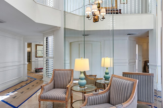 living area with crown molding, a towering ceiling, radiator, and an inviting chandelier