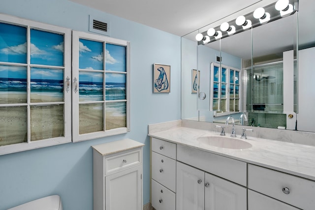 bathroom with a shower with door, vanity, and toilet