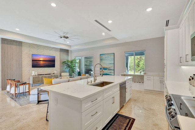 kitchen featuring sink, a kitchen island with sink, stainless steel appliances, white cabinets, and a raised ceiling