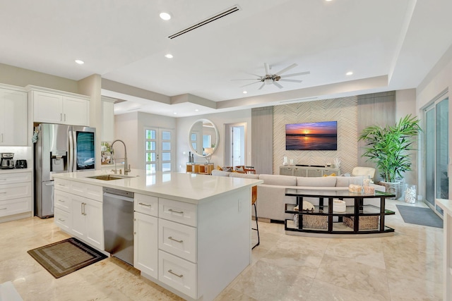 kitchen with sink, ceiling fan, stainless steel appliances, a kitchen island with sink, and white cabinets