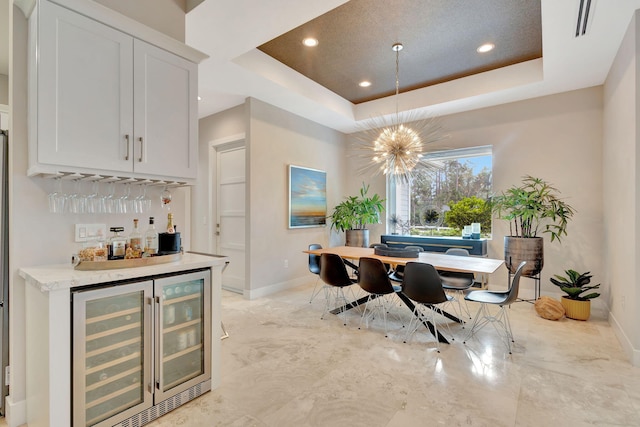 dining area with a raised ceiling, a notable chandelier, wine cooler, and indoor bar