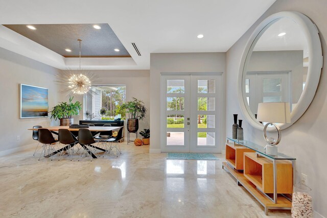 entryway featuring a raised ceiling, a chandelier, and french doors