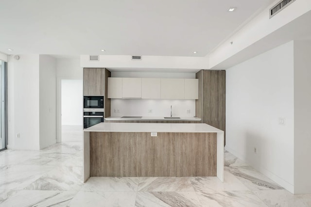 kitchen featuring black appliances, a center island, sink, and white cabinets