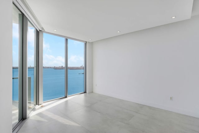 unfurnished room with a water view and a wall of windows