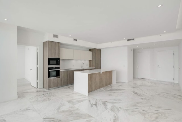 kitchen with a kitchen island, sink, white cabinets, and black appliances