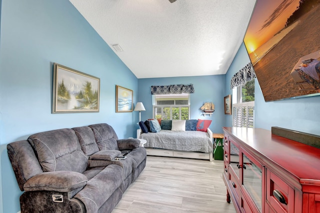 bedroom featuring lofted ceiling, light hardwood / wood-style floors, and a textured ceiling