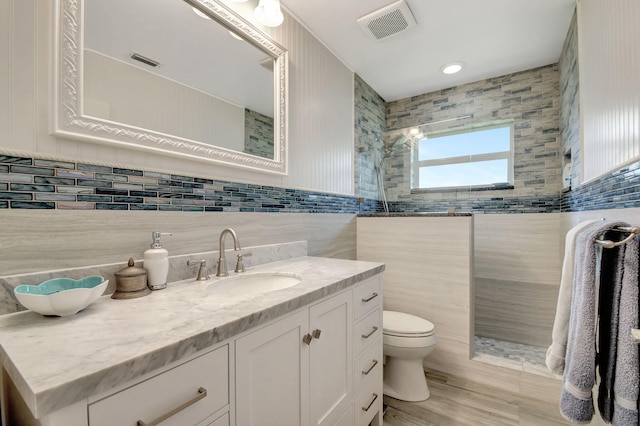 bathroom with vanity, tile walls, and toilet