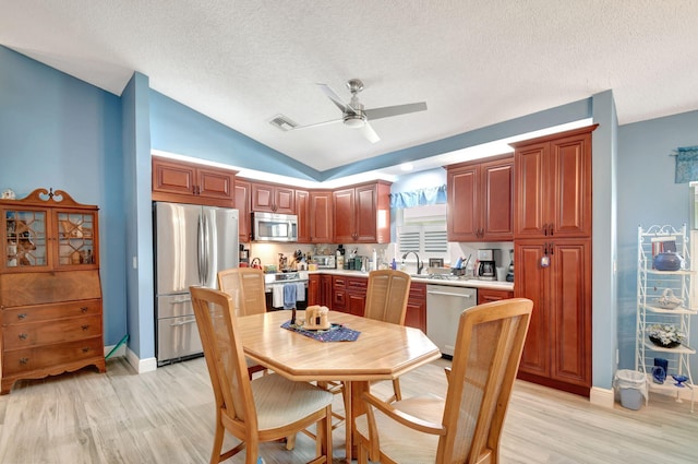 kitchen featuring ceiling fan, stainless steel appliances, sink, and light hardwood / wood-style flooring