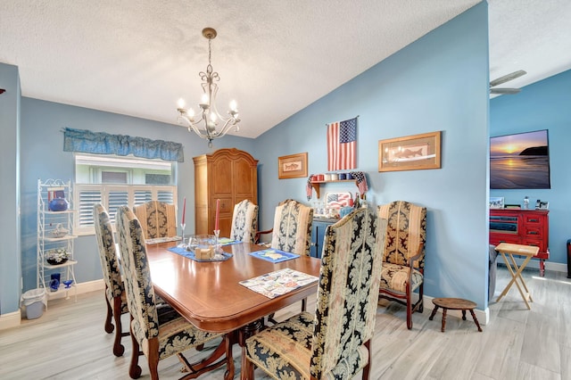 dining area with lofted ceiling, an inviting chandelier, a textured ceiling, and light wood-type flooring