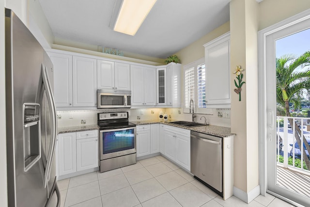 kitchen featuring sink, dark stone countertops, stainless steel appliances, tasteful backsplash, and white cabinets