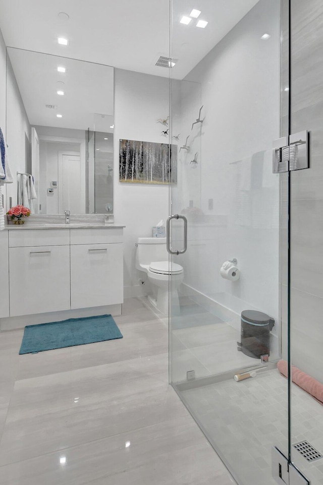 bathroom featuring tile patterned floors, vanity, toilet, and a shower with door