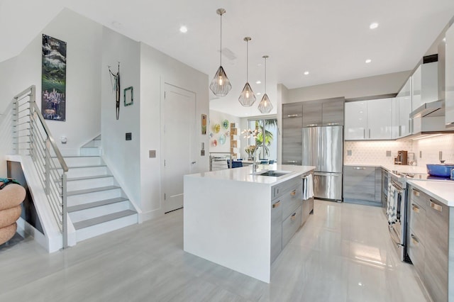 kitchen with gray cabinets, sink, hanging light fixtures, a kitchen island with sink, and stainless steel appliances