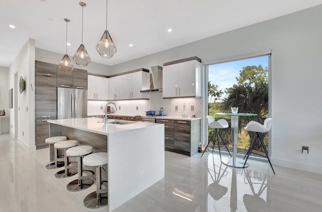 kitchen featuring pendant lighting, white cabinetry, sink, stainless steel appliances, and wall chimney exhaust hood