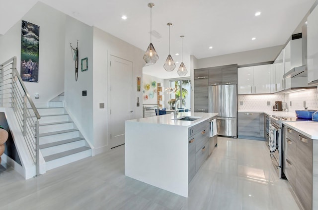 kitchen with sink, a kitchen island with sink, hanging light fixtures, gray cabinetry, and stainless steel appliances