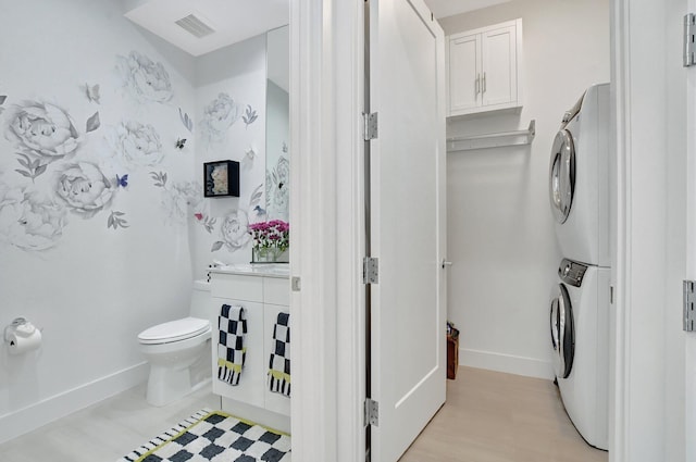 bathroom with stacked washer and dryer, vanity, and toilet